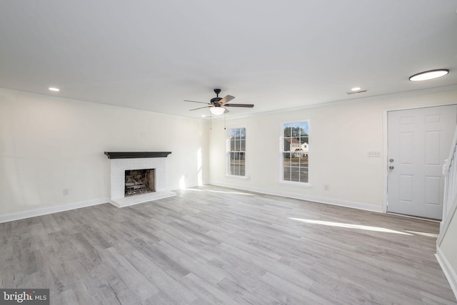 unfurnished living room featuring a fireplace, crown molding, light hardwood / wood-style flooring, and ceiling fan