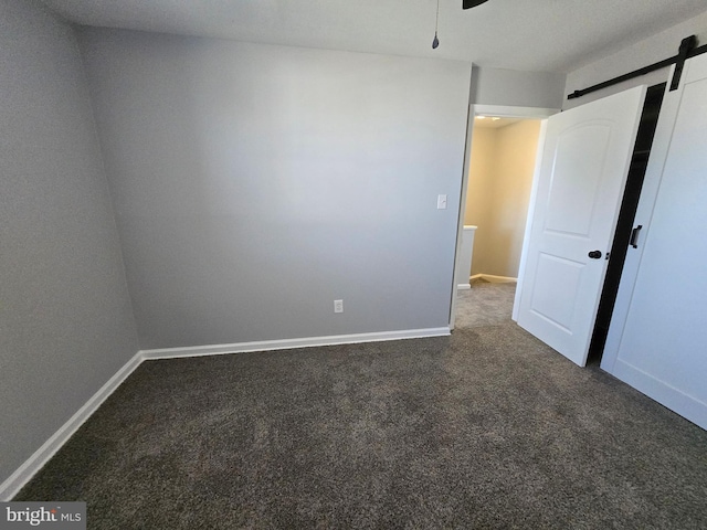 carpeted spare room featuring ceiling fan and a barn door