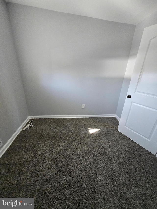 unfurnished room featuring dark carpet