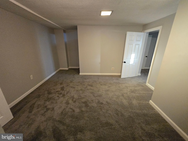 basement featuring a textured ceiling and dark colored carpet