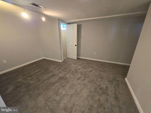 basement featuring dark colored carpet and a textured ceiling