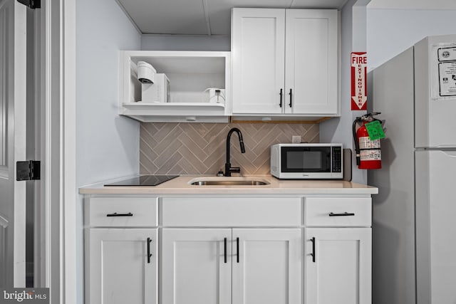 kitchen featuring tasteful backsplash, white cabinetry, sink, and white appliances