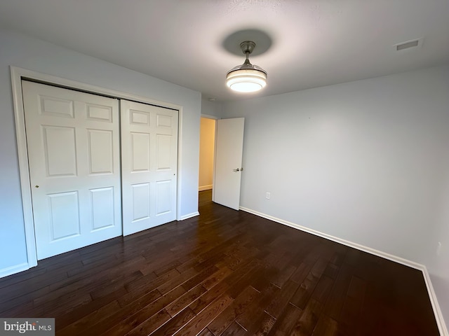 unfurnished bedroom featuring dark hardwood / wood-style floors and a closet