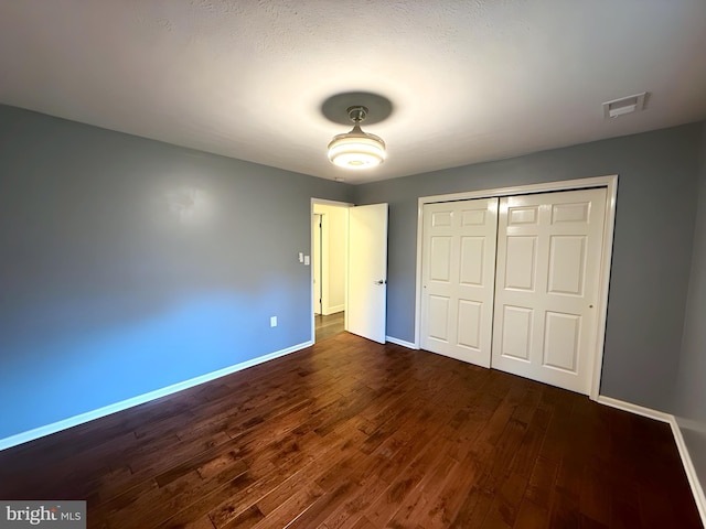 unfurnished bedroom featuring dark wood-type flooring and a closet