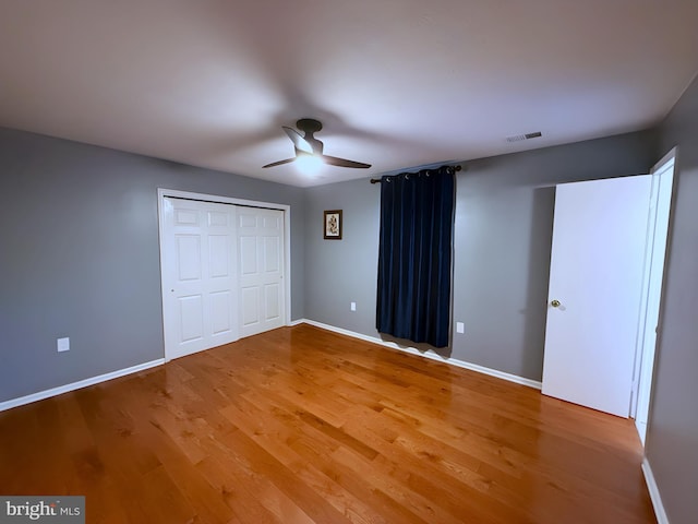 unfurnished bedroom featuring hardwood / wood-style flooring, a closet, and ceiling fan