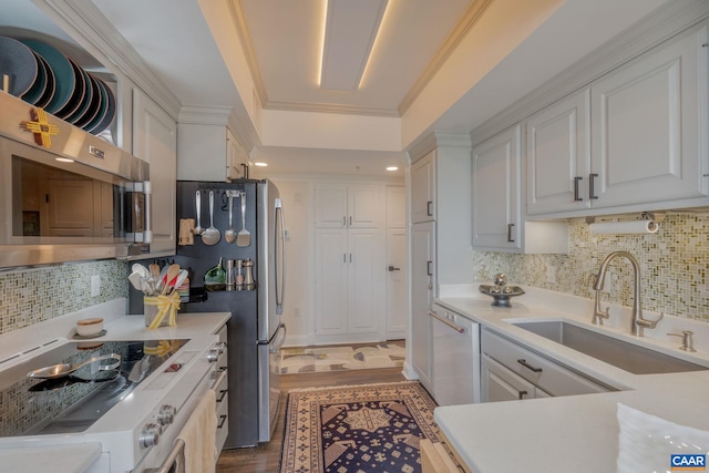 kitchen featuring sink, range, ornamental molding, white dishwasher, and white cabinets