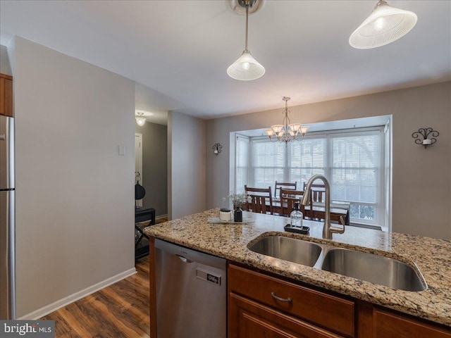 kitchen featuring appliances with stainless steel finishes, dark hardwood / wood-style floors, decorative light fixtures, sink, and light stone counters