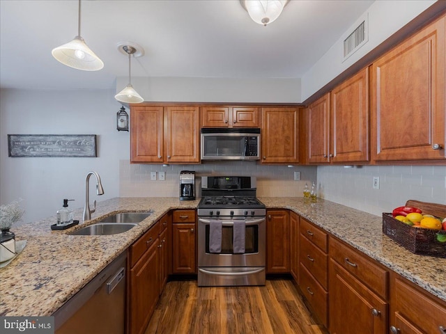 kitchen with sink, tasteful backsplash, hanging light fixtures, appliances with stainless steel finishes, and dark hardwood / wood-style floors