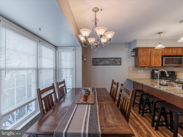 dining area featuring an inviting chandelier, sink, and dark wood-type flooring