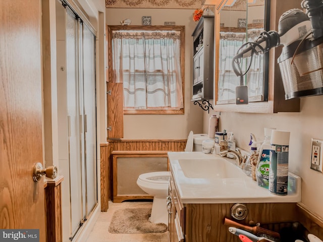 bathroom featuring vanity, toilet, and a shower with door