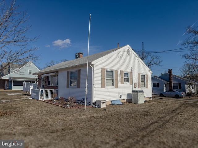 rear view of house with a yard and central AC