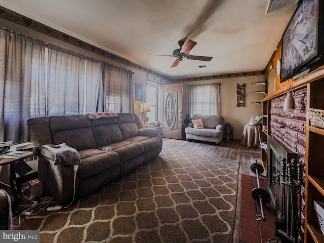 living room featuring ceiling fan, dark hardwood / wood-style floors, and a brick fireplace