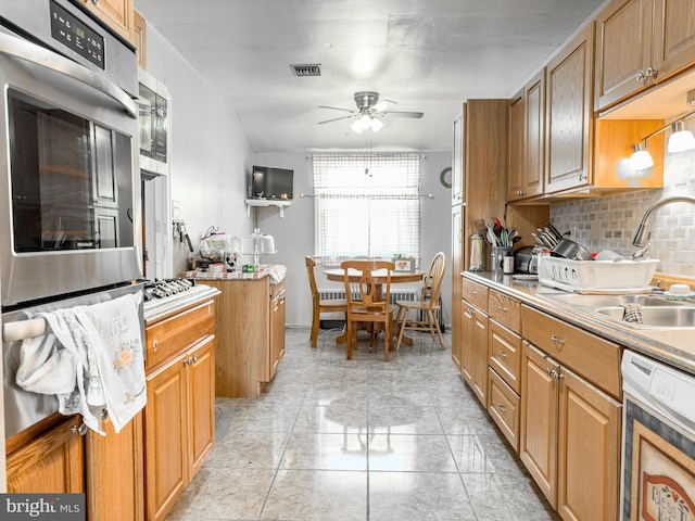 kitchen featuring stainless steel appliances, sink, backsplash, and ceiling fan