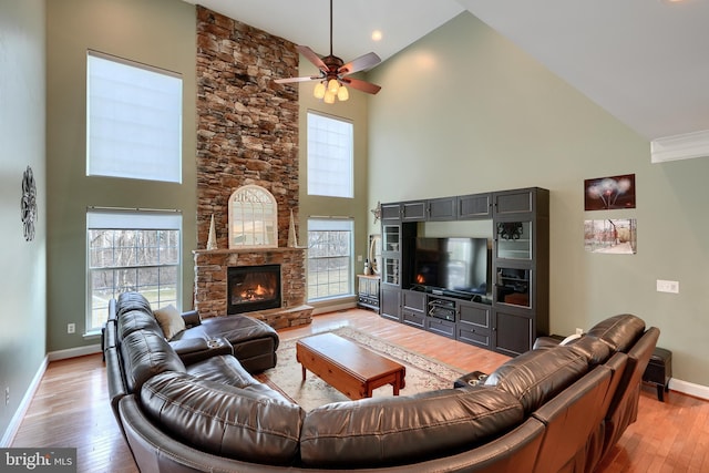 living room with a healthy amount of sunlight, a stone fireplace, and light wood-type flooring