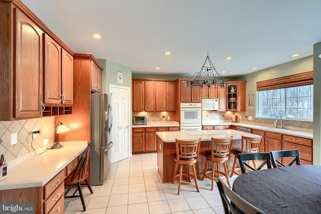 kitchen with white appliances, a breakfast bar, a kitchen island, tasteful backsplash, and light tile patterned flooring