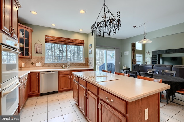 kitchen featuring light tile patterned flooring, a center island, stainless steel dishwasher, and decorative backsplash