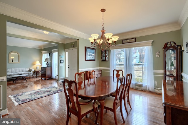 dining space featuring an inviting chandelier, crown molding, and light hardwood / wood-style flooring