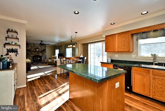 kitchen with a stone fireplace, sink, wood-type flooring, a center island, and black dishwasher