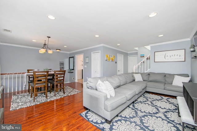 living room with wood-type flooring, crown molding, and an inviting chandelier