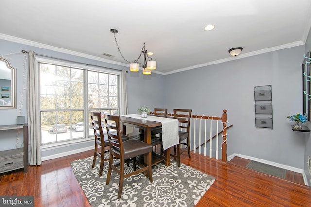 dining area with ornamental molding, dark wood-type flooring, and a notable chandelier