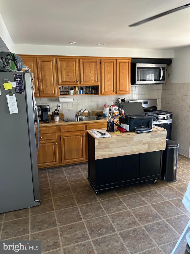 kitchen featuring appliances with stainless steel finishes, sink, and tile walls