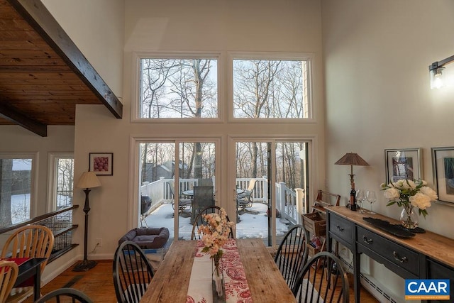 dining area with beamed ceiling, a towering ceiling, and hardwood / wood-style flooring