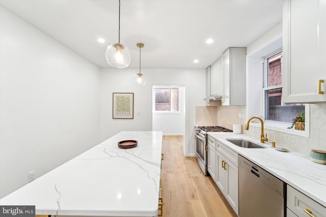 kitchen featuring pendant lighting, sink, backsplash, stainless steel appliances, and light stone countertops