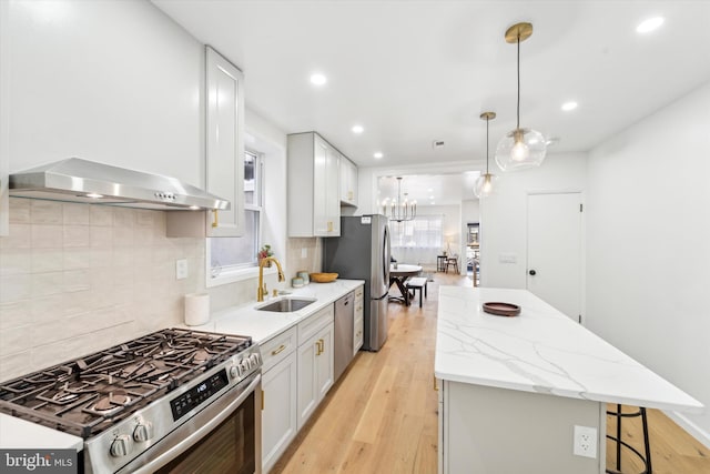 kitchen with appliances with stainless steel finishes, pendant lighting, ventilation hood, white cabinetry, and sink