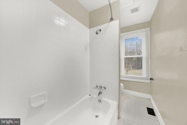 bathroom with tiled shower / bath combo, tile patterned floors, and toilet