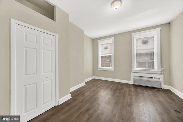 empty room with dark wood-type flooring and a wall mounted air conditioner