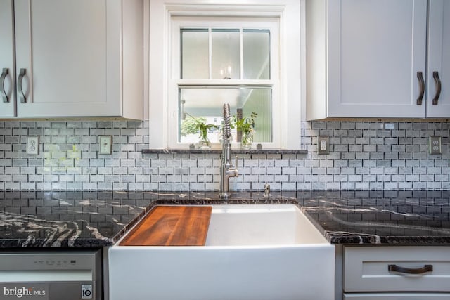 kitchen with white cabinetry, sink, dark stone countertops, backsplash, and stainless steel dishwasher