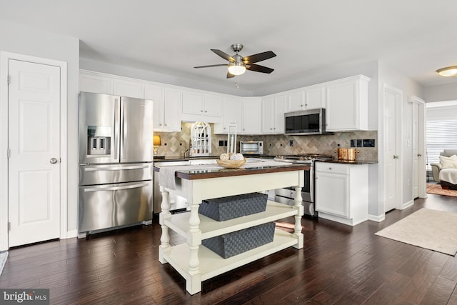 kitchen featuring white cabinets, dark countertops, dark wood-style floors, appliances with stainless steel finishes, and backsplash