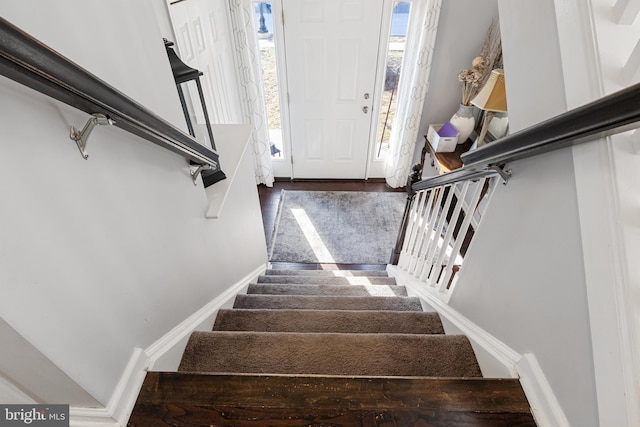 stairway featuring plenty of natural light, wood finished floors, and baseboards