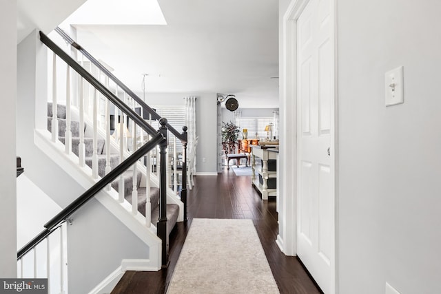 interior space featuring stairway, a skylight, dark wood finished floors, and baseboards