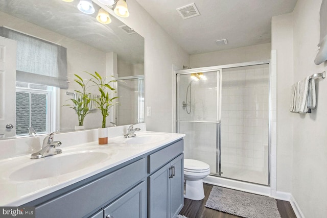 bathroom featuring walk in shower, hardwood / wood-style floors, vanity, and toilet