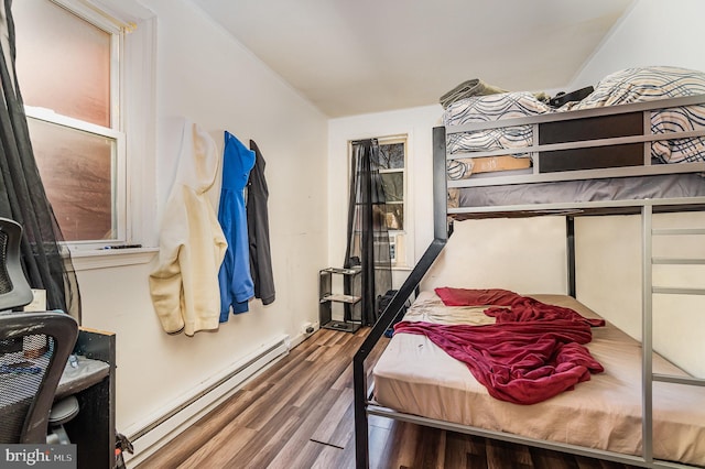 bedroom with a baseboard heating unit and wood finished floors