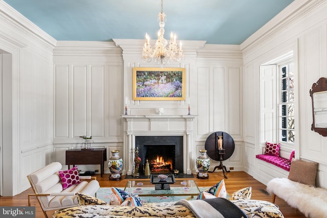 sitting room with an inviting chandelier, ornamental molding, and light wood-type flooring