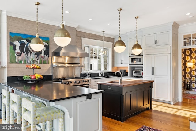 kitchen featuring range, ornamental molding, oven, a kitchen island with sink, and white cabinets