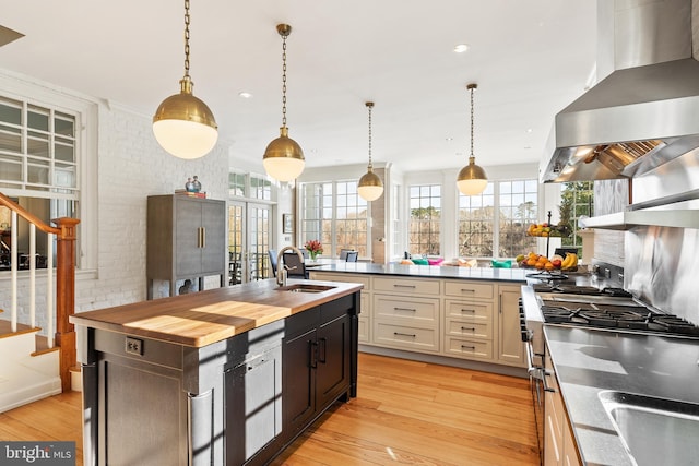 kitchen with sink, island range hood, decorative light fixtures, and an island with sink