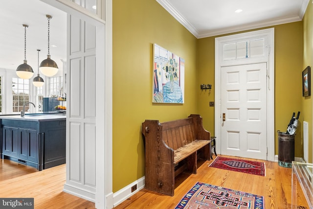 entryway featuring ornamental molding and light wood-type flooring