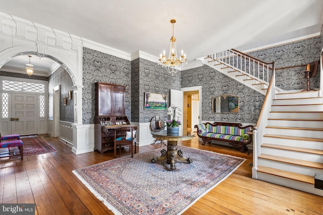 foyer featuring an inviting chandelier, hardwood / wood-style floors, and crown molding