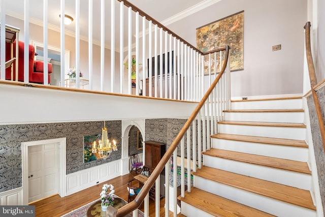 staircase featuring ornamental molding, hardwood / wood-style floors, and a notable chandelier