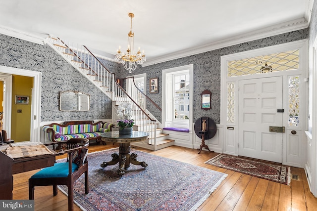 entrance foyer with crown molding, a chandelier, and light hardwood / wood-style floors