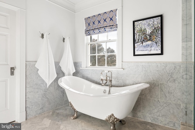 bathroom with crown molding, a tub to relax in, and tile walls