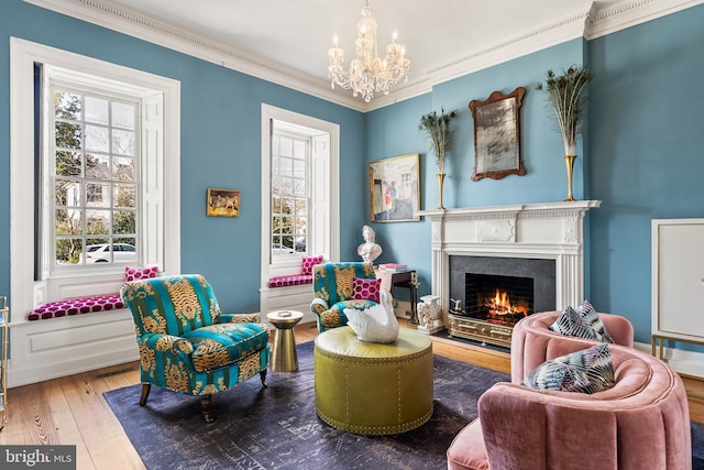 living area with hardwood / wood-style flooring, ornamental molding, and an inviting chandelier