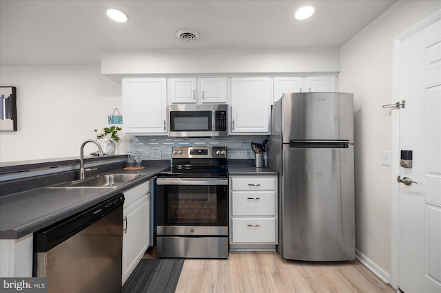 kitchen featuring stainless steel appliances, sink, decorative backsplash, and white cabinets