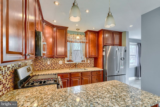 kitchen with stainless steel appliances, tasteful backsplash, sink, and decorative light fixtures