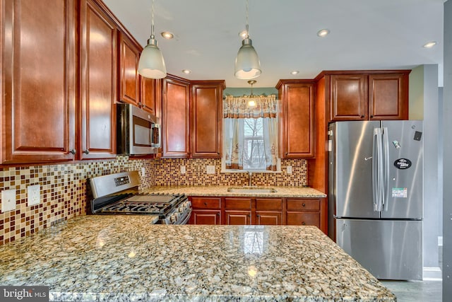 kitchen featuring appliances with stainless steel finishes, tasteful backsplash, sink, hanging light fixtures, and light stone countertops