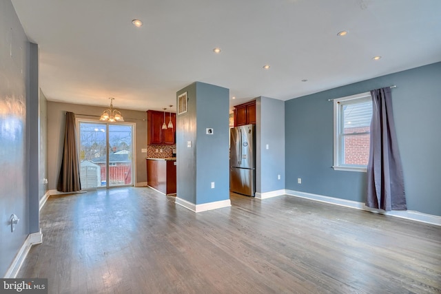 unfurnished living room with dark wood-type flooring and a notable chandelier