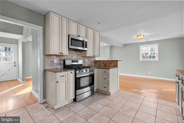 kitchen with stone countertops, decorative backsplash, light tile patterned flooring, and appliances with stainless steel finishes